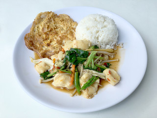 Stir vegetables with Tofu in chinese style with gravy Sauce and thai style omelet with rice in white plate on background. Vegetarian Food, healthy food.