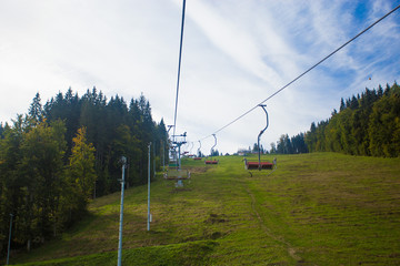 Emtpy chairlift in ski resort. Mountains and hills with in Summer with green trees