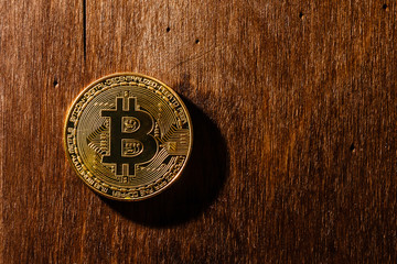 The golden bitcoin on wooden table and bokeh background, golden bitcoin symbol of bitcoin crytocurrency from blockchain technology.