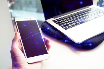 hand pick hold mobile phone with network technology and hologram web with nptebook laptop computer