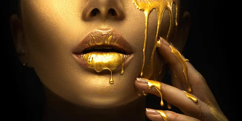 Wanddecoratie Zwart goud Gouden verfvlekken druipen van de gezichtslippen en hand, gouden vloeistofdruppels op de mond van een mooi modelmeisje, creatieve abstracte make-up. Schoonheid vrouw gezicht  © Subbotina Anna