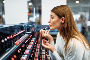 Female customer testing lip liner in make-up shop