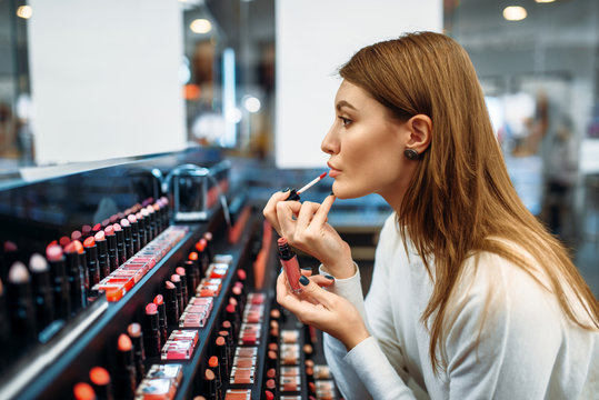 Fototapeta Female customer testing lip liner in make-up shop