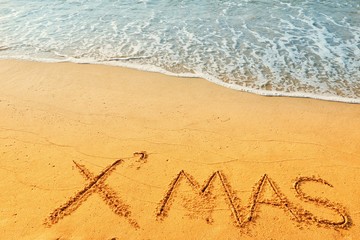 Happy new year concept, Xmas handwriting on sand beach.