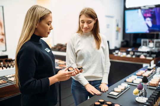 Fototapeta Consultant shows powder to woman in make-up shop