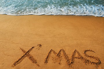 Happy new year concept, Xmas handwriting on sand beach.