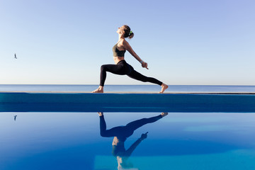 Young attractive woman practicing yoga stand in Warrior one exercise, Virabhadrasana pose, working...