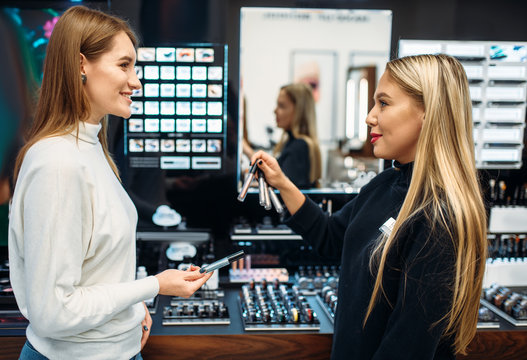 Fototapeta Seller shows to client eyeshadows in make-up shop