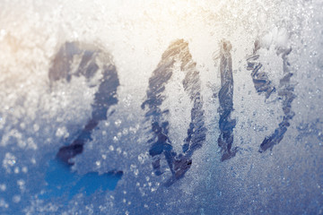 inscription  2019 on a frozen window in hoarfrost. Scratched numbers on blue cold winter background