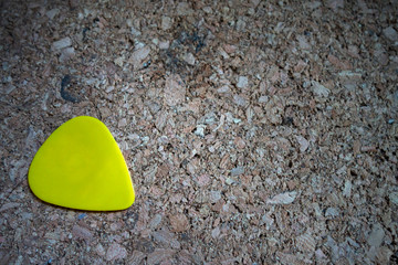 Yellow guitar pick on wood plate with copy space