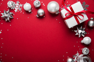 Merry Christmas and Happy Holidays greeting card, frame, banner. New Year. Noel. Christmas white and silver ornaments on red background top view. Winter holiday xmas theme.