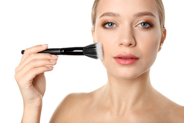 Portrait of beautiful young woman with makeup brush on white background