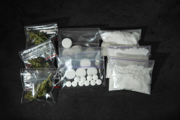 Cocaine, dried hemp and ecstasy on dark table, top view
