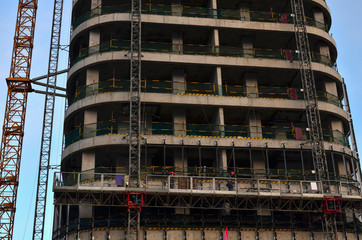 Construction workers in mobile hydraulic construction platform. Repair of the facade of the building. Multi-storey building. Construction of multi-storey residential building