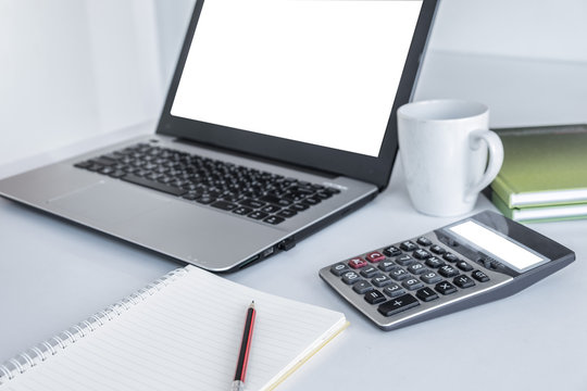 Laptop White Screen ,calculator White Screen ,white Coffee Mug, Green Book And A Pencil Placed Over Notebook. All On The White Desk