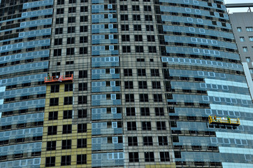 Construction workers in mobile hydraulic construction platform. Repair of the glass facade of the building, background, structure, abstraction