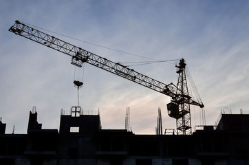 Construction of a high-rise building with a crane. Building construction using formwork. The construction crane and the building against the blue sky.