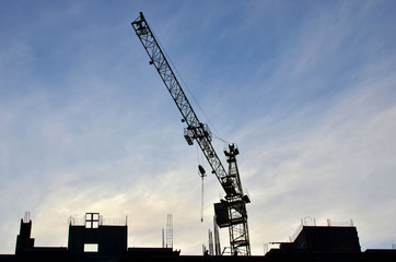 Construction of a high-rise building with a crane. Building construction using formwork. The construction crane and the building against the blue sky.