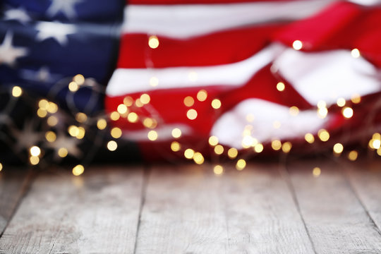 Blurred lights and American flag on wooden table. Mockup for design