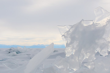 Fototapeta na wymiar ice floes on a shore of mountainous lake, transparent splinter close-up