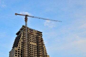 Fototapeta na wymiar Crane and building construction site against blue sky with blank white billboard for advertisement at the top of tower architecture on the background of the sky