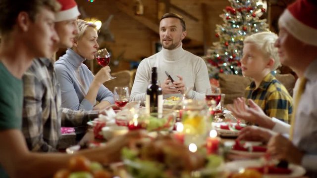 Head of the family takes group selfie with his family on smartphone by Christmas table