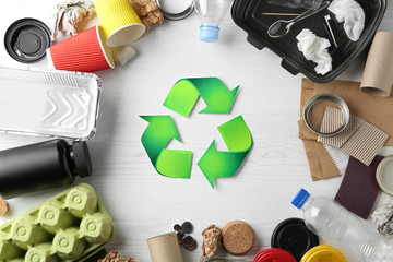 Recycling symbol and different garbage on wooden background, top view