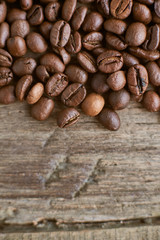 Roasted coffee beans on rustic wooden background. Food ingredients, top view, space for text