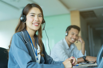 close up focus on asian call centre woman with team working by talking on headphone trying to response answer or working in operation office room.helpdesk hotline concept.	
