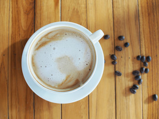 Top view hot coffee with seed on wooden table in white coffee, foam no picture