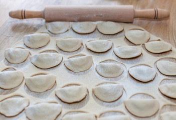Dumplings raw on a wooden board. Traditional homemade food. The process of cooking dumplings. 