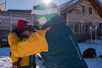 father preparing his little son for the first time on a snowboard