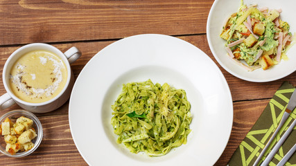 Pasta with spinach in a plate on a wooden background, top view
