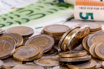 Euro banknotes rolled and euro coins in different positions on a white background detail