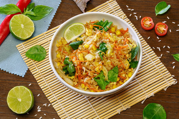 Chinese rice wok with meat and vegetables in a plate on a wooden background