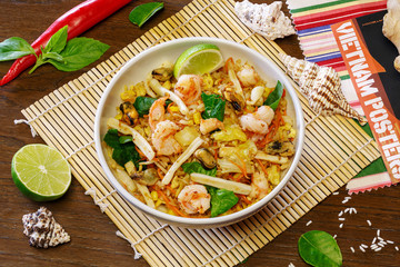 Chinese rice wok with meat and vegetables in a plate on a wooden background