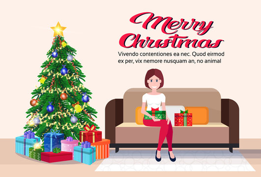 woman sitting on couch modern living room merry christmas happy new year decorated gift boxes pine tree flat horizontal copy space