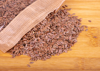 Flax seeds in a transparent package on a wooden background