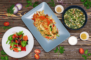 Soup, salad and meat dish on wooden background, top view