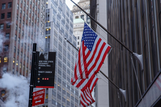 NEW YORK CITY, NY - AUGUST 21, 2014: Famous Wall street and the building in New York, New York Stock Exchange with patriot flag - Powered by Adobe