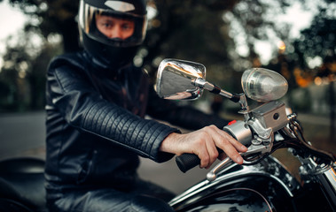 Fototapeta na wymiar Biker in helmet poses on classical chopper
