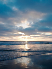 Fototapeta premium The sun setting into the Pacific ocean seen from a beach in southern California, USA