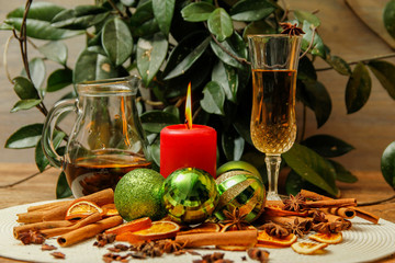 Holiday Christmas decoration with white wine, Christmas ball, candle, dried orange, anise stars and sticks of cinnamon. Wooden table and vintage background.