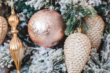 Christmas tree with beautiful winter decorations, pink ball, white cones, golden icicles, pink tape and snowflackes on the brunches. Closeup picture. Home interior. New Year holidays.