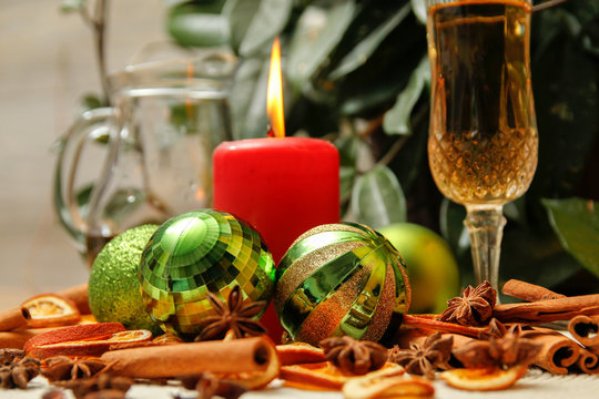 Holiday Christmas decoration with white wine, Christmas ball, candle, dried orange, anise stars and sticks of cinnamon. Wooden table and vintage background. - Powered by Adobe