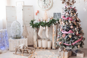 Christmas interior decorations, christmas tree with many balls, toys and pink tape, fireplace with big candles and woolen white socks, big clocks on the background, sled and white bear
