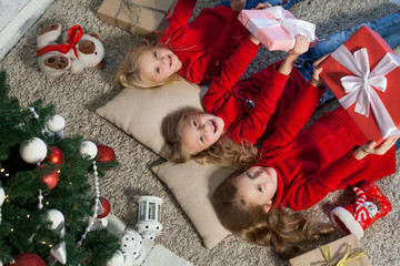 Fototapeta na wymiar two small girls blondes lie near a Christmas tree gifts new year holiday