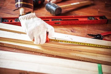 Building DIY while used tape measure. Professional carpenter working with wood and building tools in house for renovate.