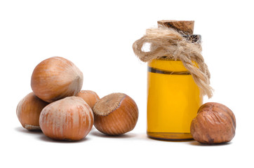Hazelnut nut oil in the bottle and heap of hazelnuts isolated on the white background.