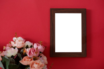 Mock-up wooden photo frame with space for text or picture on red background and flower.